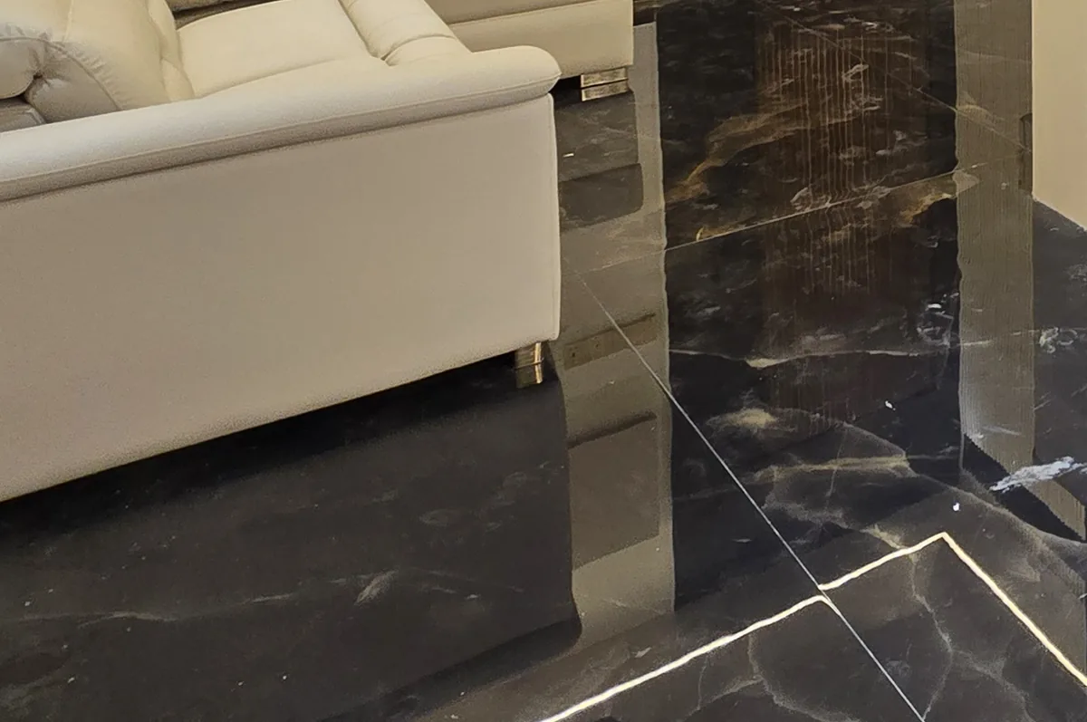 Polished dark marble floor with gold veining in a finished living room, beside a cream sofa