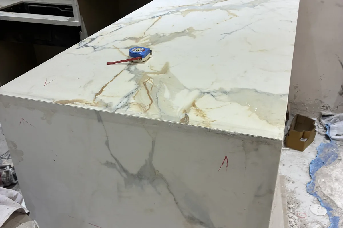 Large-format white slab with gold veining installed as a kitchen counter, edges mitred