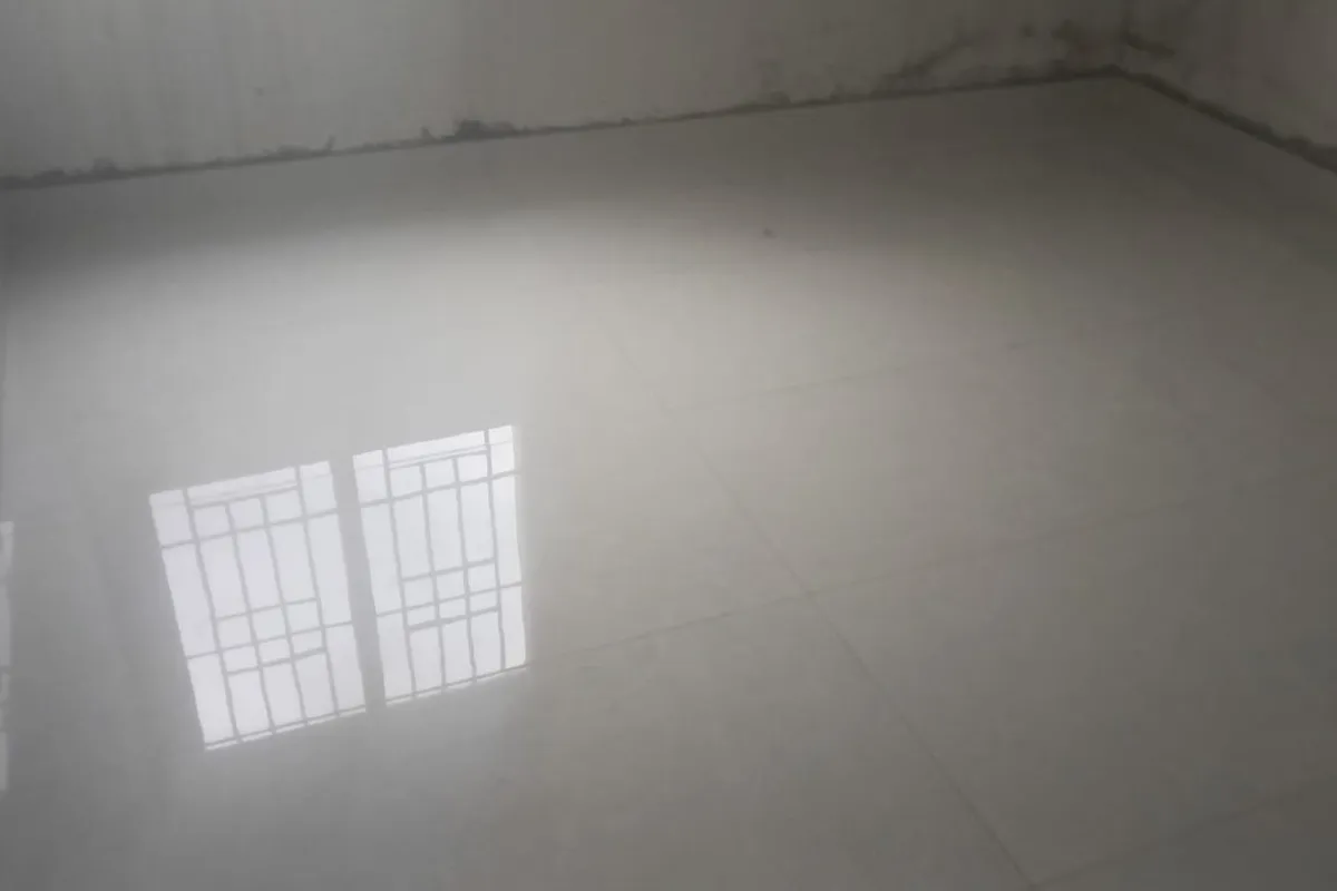 Finished polished floor tiles with tight, even joints, a window reflected in the surface
