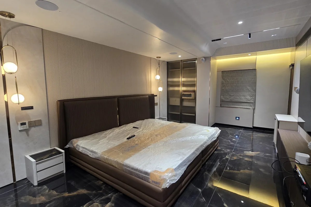 Finished bedroom with a polished black marble floor veined in gold, bed and wardrobes installed