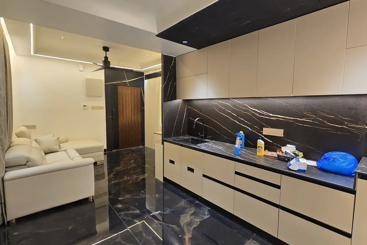 Finished open kitchen and living area with a polished black-and-gold marble floor and a matching dark stone kitchen backsplash