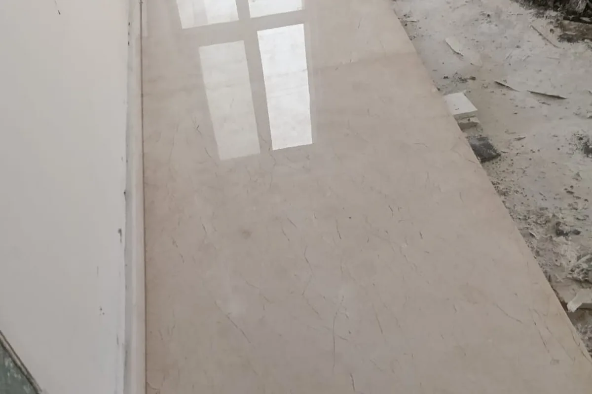 Polished beige floor with soft veining reflecting a window, edges still to be finished
