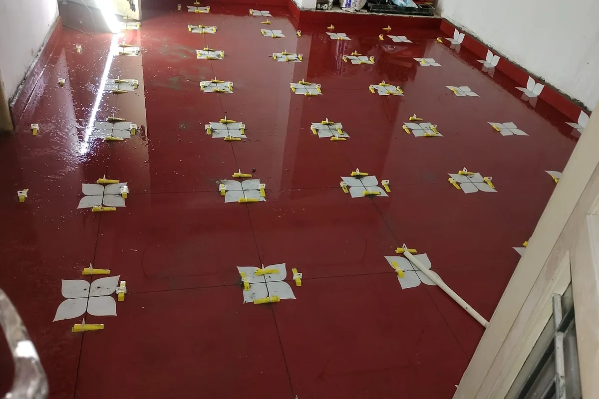 Deep red polished floor tiles held flat with leveling clips during installation